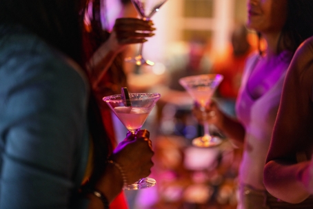People holding cocktails at a lively social gathering, representing how holiday parties and nights out can lead to serious alcohol-related charges in Virginia.