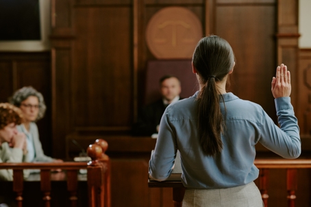 Woman testifying in a courtroom with a judge and attorneys present.