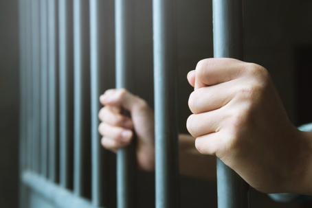 Person gripping jail bars during pretrial detention